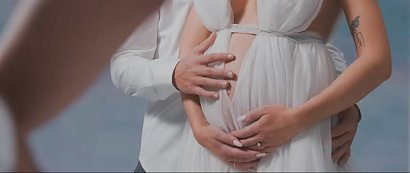 - biała sukienka odsłaniająca goły ciążowy brzuszek. W teledysku...